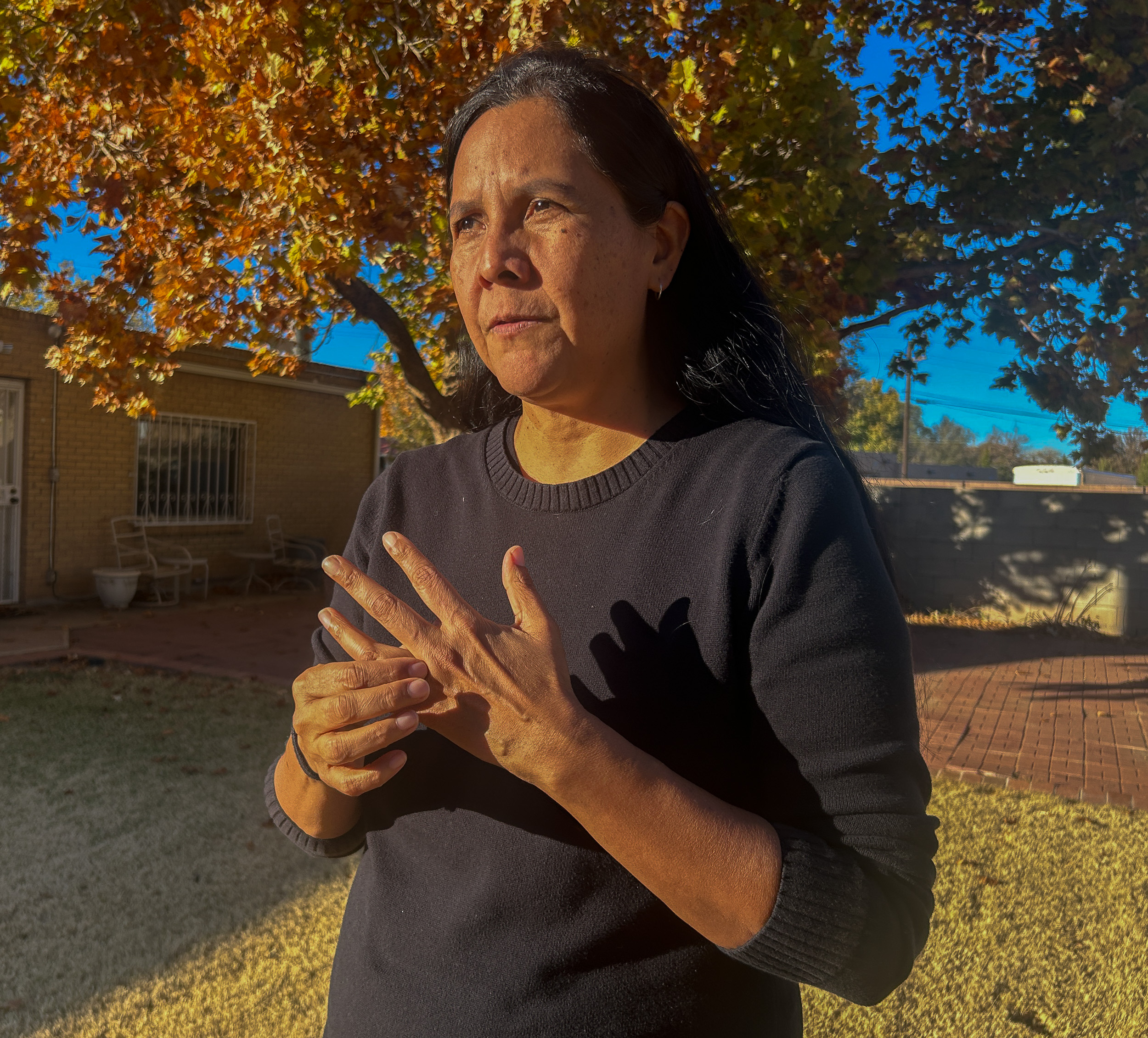 A woman with long dark hair faces the sun while touching her finger where she wears a ring that she got at the Navajo Nation Fair as a teenager.